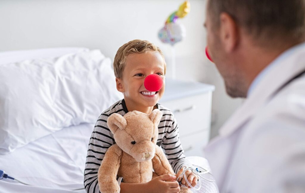 Paediatric consultant and small boy wearing red noses
