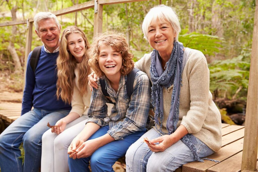 Grandparents sitting on a walkway in the forest with their grandchildren.