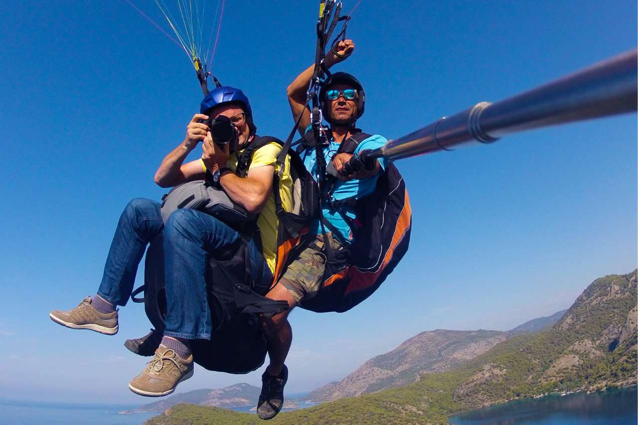 Two men having fun taking photos while dual paragliding.