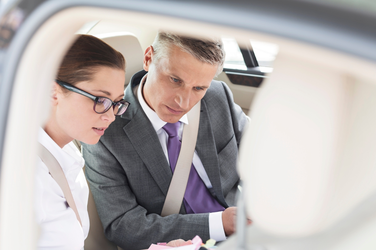 Removal of non domicile tax system Business and woman looking at laptop in the rear of a chauffeur driven car. Removal of non domicile tax system.